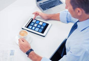 business, people and technology concept - businessman with application icons on tablet pc drinking coffee in office