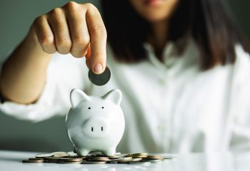 Hand,Putting,Coin,On,Pig,Saving.,Business,,Investment,,Retirement,,Finance Hand putting coin on pig saving. business, investment, retirement, finance and Money Saving for the future concepts.