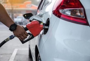 Closeup of woman pumping gasoline fuel in car at gas station. Petrol or gasoline being pumped into a motor vehicle car.
