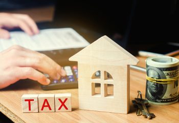 Wooden house with the inscription "Tax". Taxes on real estate, payment. Penalty, arrears. Register of taxpayers for property. Law-abiding, evasion of payment. Court law