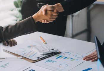 Handshake in agreement against young business people in board room meeting