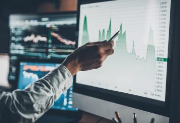 Close-up of young businessman pointing on the data presented in the chart with pen while working in creative office