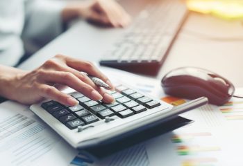 Close up hand of business woman accountant or banker making calculations. Savings, finances and economy audit debt concept