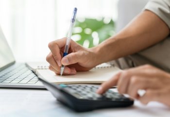 Man is calculating annual tax with calculator and filling form of Individual Income Tax Return. Season to pay Tax and Budget planning concept.