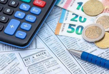 French payroll with social contributions and income tax deduction, mandatory in France since January 2019, along with a calculator, a pen, and euro coins and bank notes